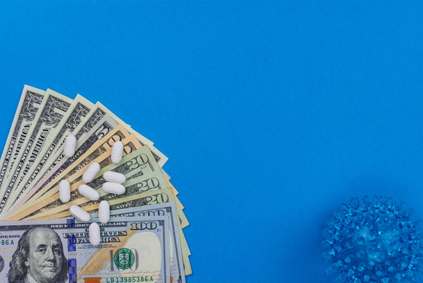 Healthcare cost concept. US Dollars with scattered medicine pills on blue background. - Fotografie, Obrázek