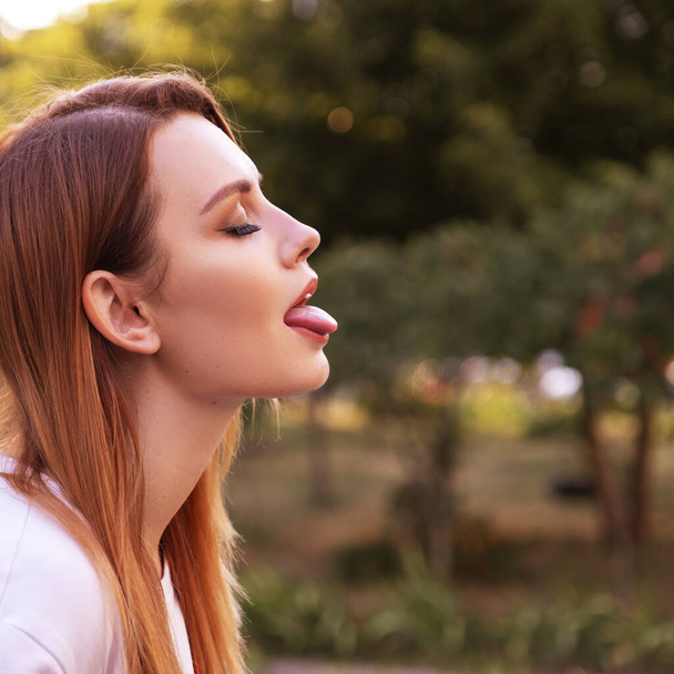 Frau mit geschlossenen Augen im Park. Sie lernt Zungenküssen. Raum für Text. - Foto, Bild