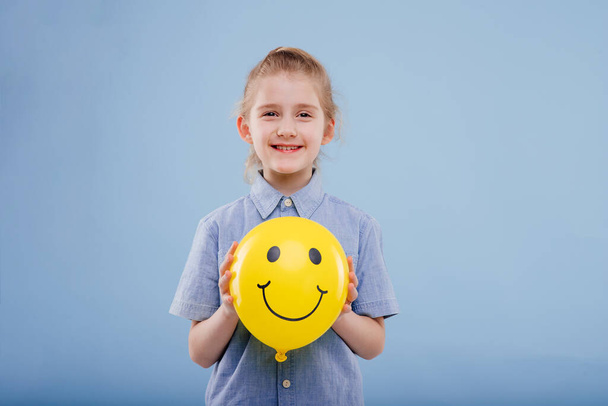 little girl with yellow balloon with smile. looks at the camera, - Foto, Imagen