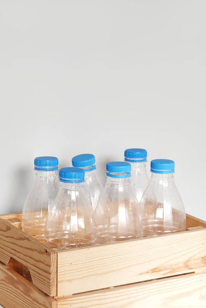 Plastic bottles with blue caps for recycling in a wooden box.  - Fotografie, Obrázek