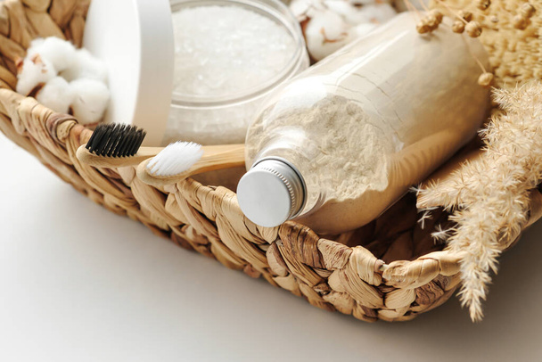 Produits cosmétiques spa et bien-être : gommage corporel, brosses à dents en hêtre, sel de bain marin, savon, peigne en bois dans un panier en osier
 - Photo, image