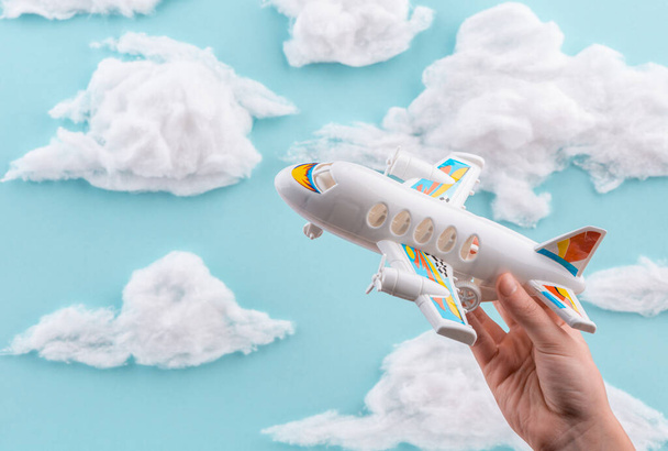 White airplane toy in childs hand flying through handmade sky - Фото, зображення