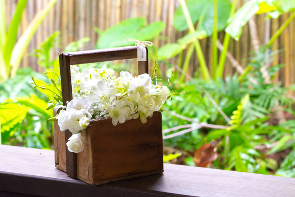 Gorgeous bridal wedding bouquet of white roses, hydrangeas, ozotamnusa,eucalyptus and orchid in wood basket on beautiful concrete path with green left background - Photo, Image