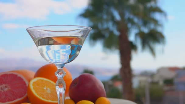 Uma azeitona verde está caindo em um copo com vermute Martini
 - Filmagem, Vídeo
