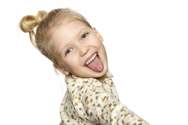Portrait of funny little girl showing her tongue, isolated over white background with copy space. - Photo, Image
