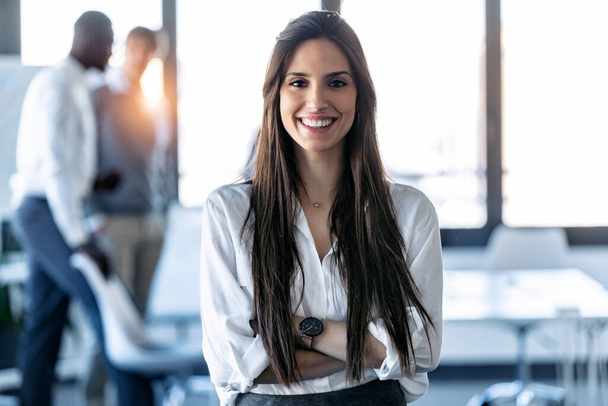 Shot of smiling young businesswoman looking at camera while standing in the coworking space. - Photo, Image