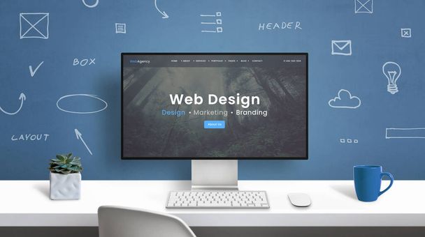 現代のコンピュータモニタ上のウェブデザインスタジオのホームページ。壁にWebデザイン要素の図面とオフィスデスク - 写真・画像
