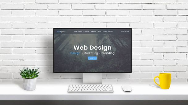 Concept de studio de conception Web avec écran d'ordinateur et page Web de l'agence de conception Web. bureau propre avec plante, clavier, souris et tasse à café. Mur de briques blanches en arrière-plan
 - Photo, image