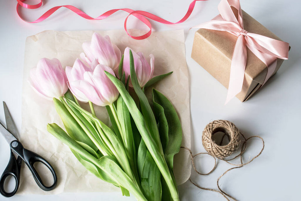 O buquê de tulipas laranja é rosa. Dom, papel de embrulho, fitas, tesouras
. - Foto, Imagem