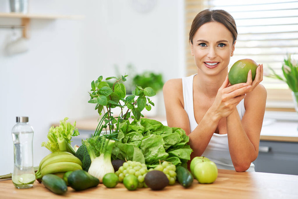 Egészséges felnőtt nő zöld étellel a konyhában - Fotó, kép