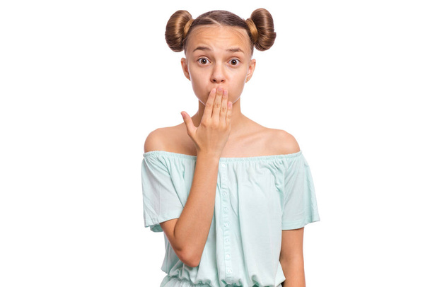 Portrait of surprised teen girl, isolated on white background. Funny child looks at camera in amazement, touching face with hands, covering mouth. Beautiful caucasian teenager, opens eyes with shock. - Photo, Image