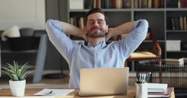 Satisfied employee relaxing at office desk holding hands behind head - Felvétel, videó