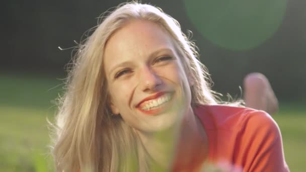 PORTRAIT: Attractive blonde woman lies in the grass and laughs on a sunny day. - Footage, Video