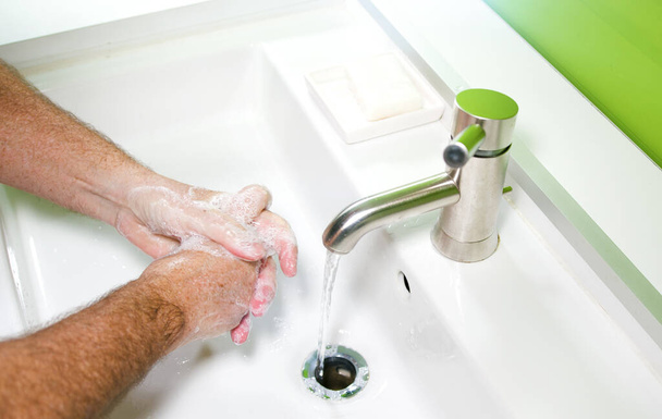 ウイルス感染を防ぎ石鹸と水で汚れた手をきれいにするために手を洗う男 - 写真・画像