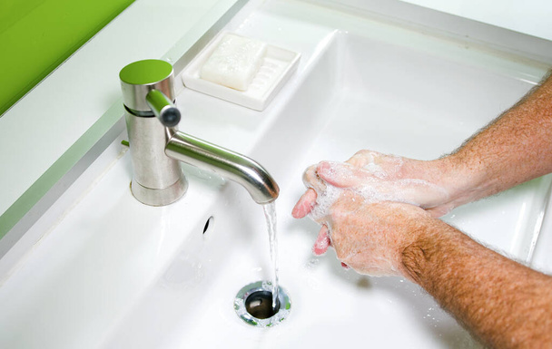 ウイルス感染を防ぎ石鹸と水で汚れた手をきれいにするために手を洗う男 - 写真・画像