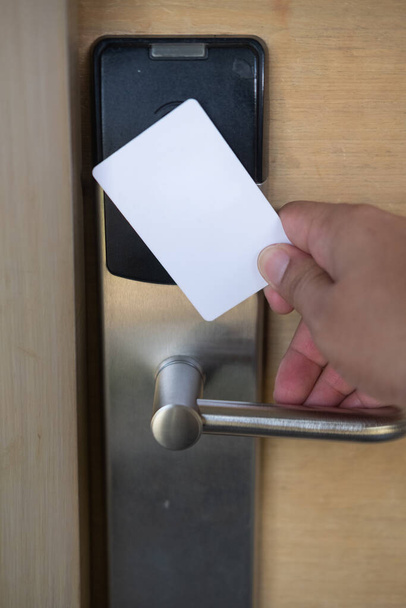 男の手はホテルの部屋のドアを開くためにキーカードスイッチを使用します。ドアのロックとロックを解除するドアのアクセス制御スキャンキーカード用の磁石カードを保持 - 写真・画像