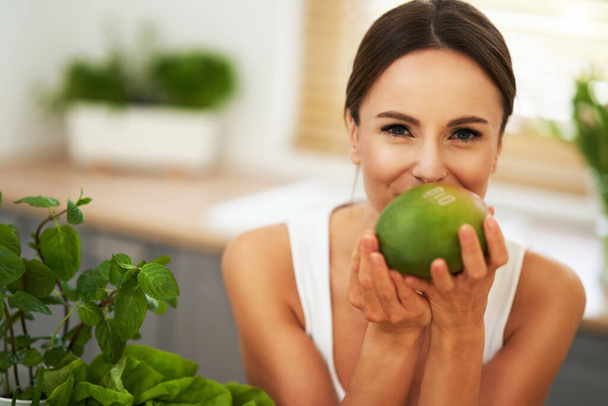 Mujer adulta saludable con comida verde en la cocina
 - Foto, imagen