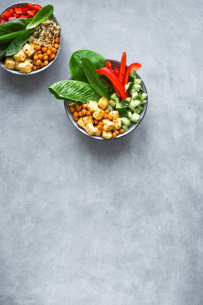 Vegan lunch bowl, balanced healthy eating buddha bowl. Fried tofu, quinoa, chickpea, cucumber, romane, bell pepper, seeds and greens vegetables salad, top view, copy space. - Foto, Imagem