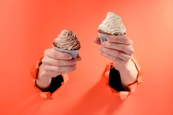 Két muffint tartó kezek, gyönyörű körkörös cukormázzal. - Fotó, kép