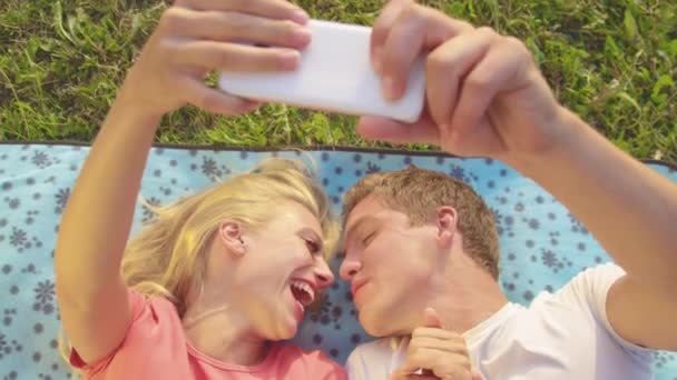 Sluiten: Schattige pasgetrouwden kussen als ze liggen op de deken en selfies nemen. - Video