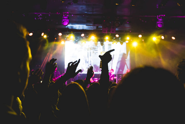 Ένα πλήθος ανθρώπων σηκώνουν τα χέρια τους κατά τη διάρκεια μιας συναυλίας. Απολαμβάνουν τη μουσική. Επιλεκτική εστίαση. - Φωτογραφία, εικόνα