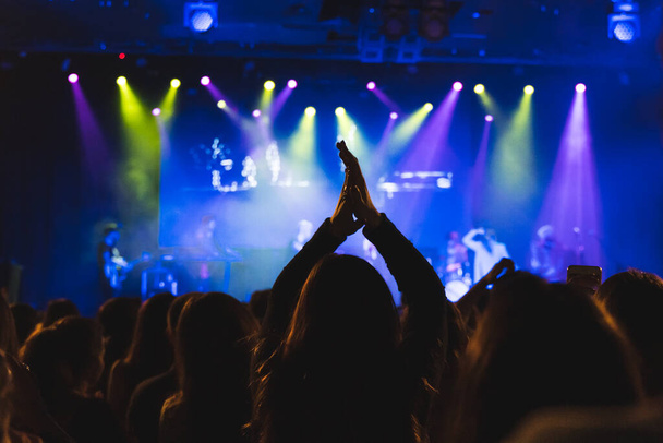 Ένα πλήθος ανθρώπων σηκώνουν τα χέρια τους κατά τη διάρκεια μιας συναυλίας. Απολαμβάνουν τη μουσική. Επιλεκτική εστίαση. - Φωτογραφία, εικόνα
