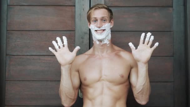 guy with shaving foam on face and fingers near vintage door - Materiał filmowy, wideo