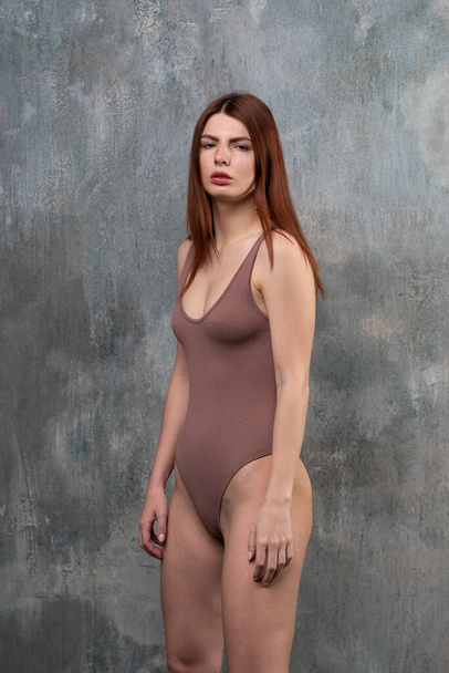 young beautiful girl posing in brown bodysuit in studio - Fotoğraf, Görsel
