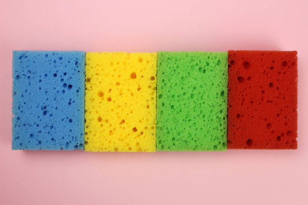 Colorful sponges for washing dishes or cleaning the home on a pink background. The view from the top - Фото, изображение