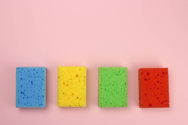 Colored sponges for dishes or home cleaning on a pink background - 写真・画像