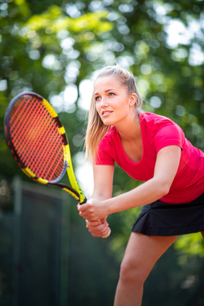 Pretty, young woman tennis player playing on a clay court. Healthy active lifestyle concept - Zdjęcie, obraz