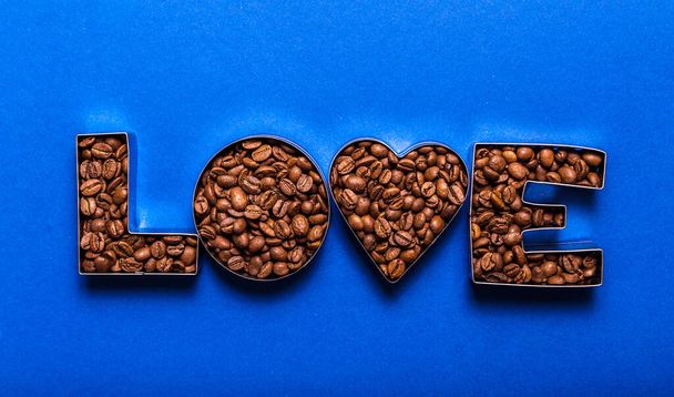 Mavi arka planda kahve çekirdeklerinden yapılmış aşk mektupları. Kahve aşkı konsepti. Üst görünüm - Fotoğraf, Görsel