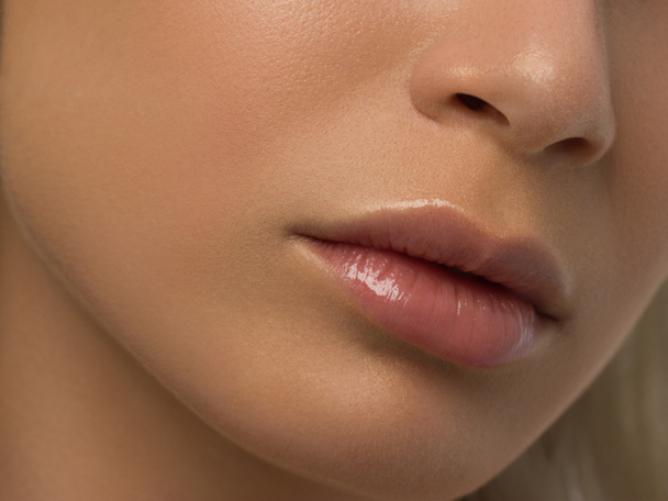 Sexual full lips. Natural gloss of lips and woman's skin. The mouth is closed. Increase in lips, cosmetology. Pink lips and long neck. Gentle pure skin and wavy blonde hair. - Fotoğraf, Görsel