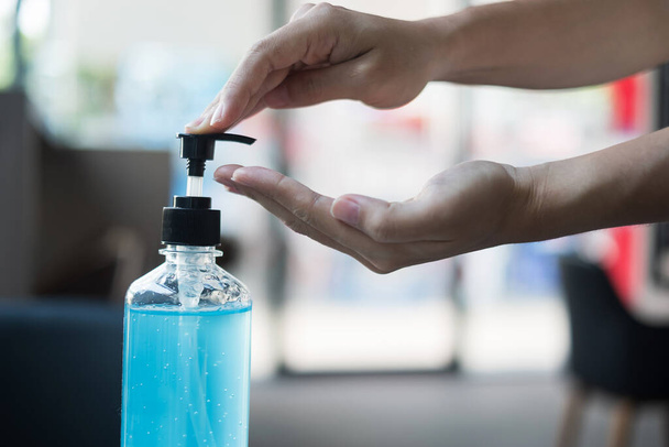 Woman hands using wash hand sanitizer gel dispenser, against Novel coronavirus or Corona Virus Disease (Covid-19) at public train station. Antiseptic, Hygiene and Healthcare concept - Фото, изображение
