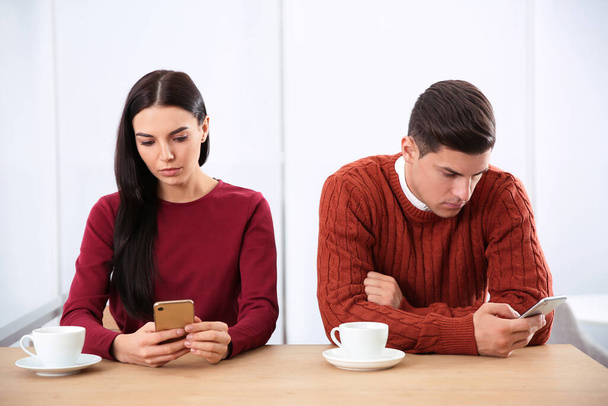 Couple addicted to smartphones ignoring each other in cafe. Relationship problems - Foto, imagen