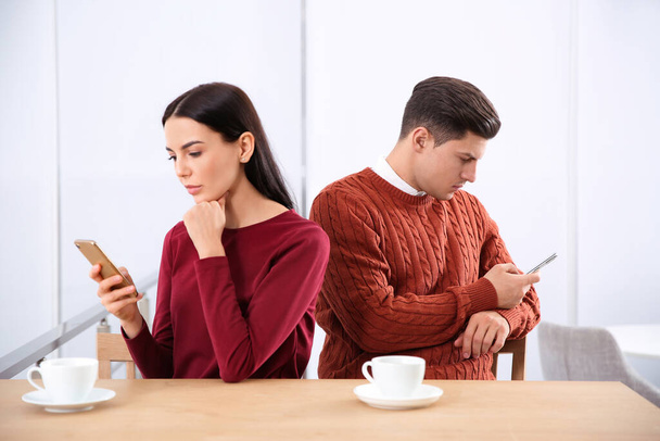 Couple addicted to smartphones ignoring each other in cafe. Relationship problems - 写真・画像