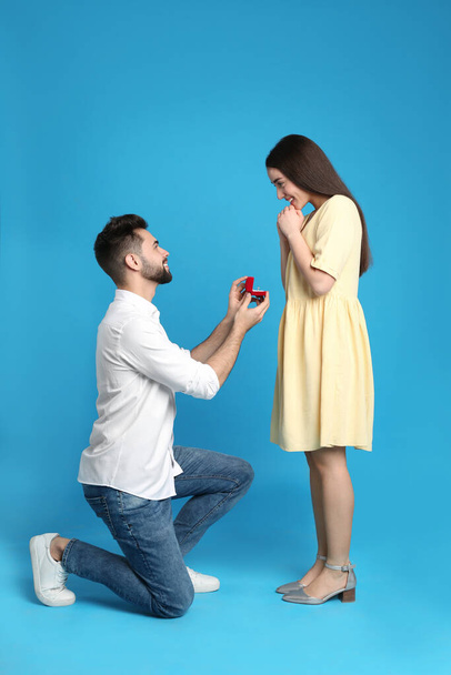 Man with engagement ring making marriage proposal to girlfriend on blue background - Photo, image