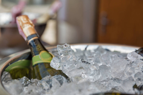 Sparkling wine bottle in ice bucket closeup - Foto, Imagen