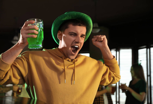 Emotional man with glass of green beer in pub. St. Patrick's Day celebration - Φωτογραφία, εικόνα