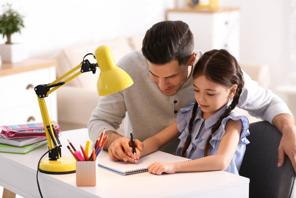 Man helping his daughter with homework at table indoors - Foto, Imagen