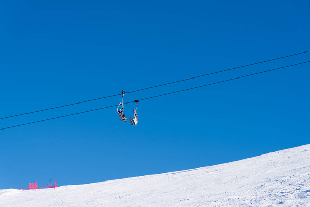 Bulgaria. Bansko. 10 February 2020.Ski resort in Bansko. Snowy ski slopes and  chair ski lifts station in  winter mountain ski resort. Under blue sky on sunny day - Foto, immagini