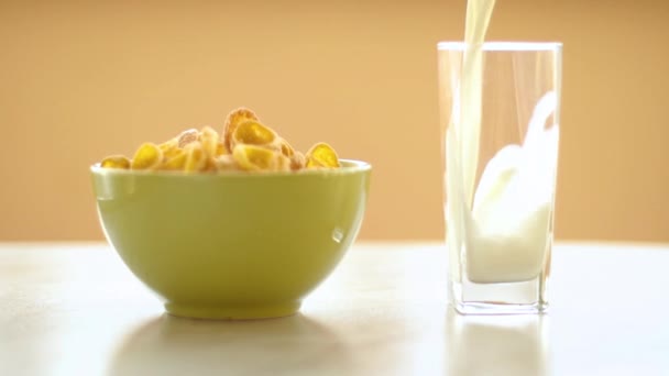 緑の皿の中のコーンフレーク牛乳がガラスに流れ込み - 映像、動画