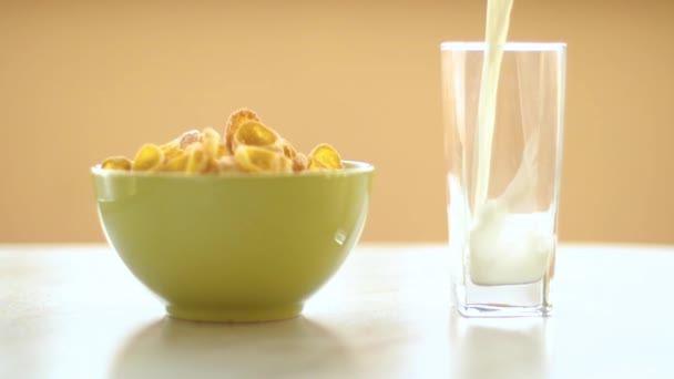 cornflakes στο πράσινο πιάτο, το γάλα ρέει στο ποτήρι, αργή κίνηση - Πλάνα, βίντεο
