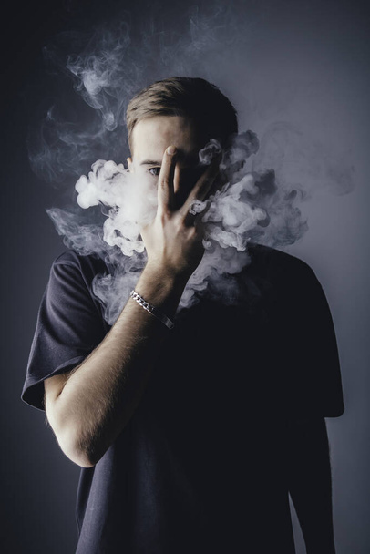 Young man with smoke in front of head - Foto, afbeelding