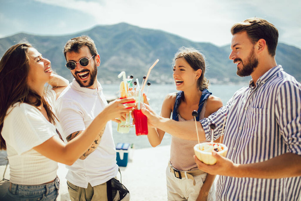 Φίλοι στην παραλία πίνοντας κοκτέιλ διασκεδάζοντας στις καλοκαιρινές διακοπές - Φωτογραφία, εικόνα