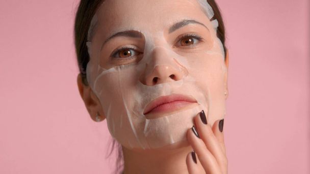 30s brunette woman closeup portrait showing a sheet mask on. Self-care concept - Photo, Image