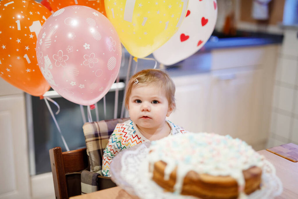 Adorable petite fille qui fête son premier anniversaire. Bébé manger des marshmellows décoration sur gâteau fait maison, intérieur. Fête d'anniversaire pour mignon tout-petit enfant, belle fille - Photo, image