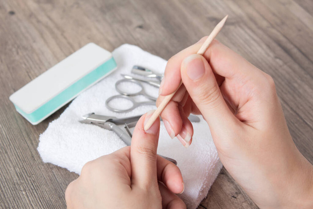Manicure. Push back the cuticle with an orange tree stick. Getting injured during a manicure. Skin care, hygiene. Spa, nail salon. Home care. Beauty. - Φωτογραφία, εικόνα
