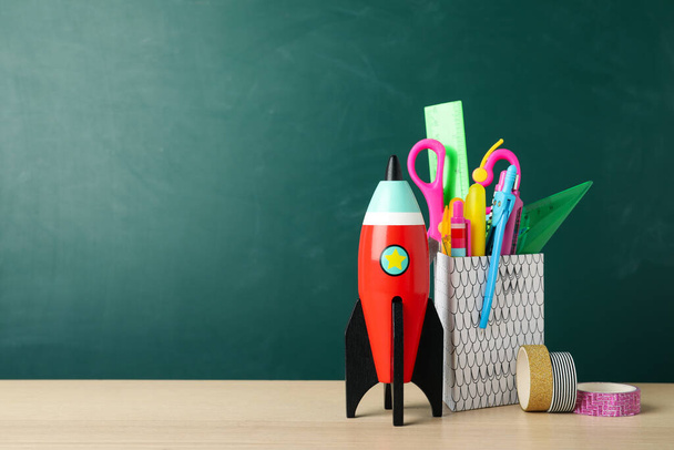 Bright toy rocket and school supplies on wooden desk. Space for text - Фото, зображення