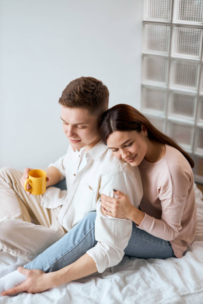 young man holding a yellow mug and striking his wifes leg - Foto, imagen